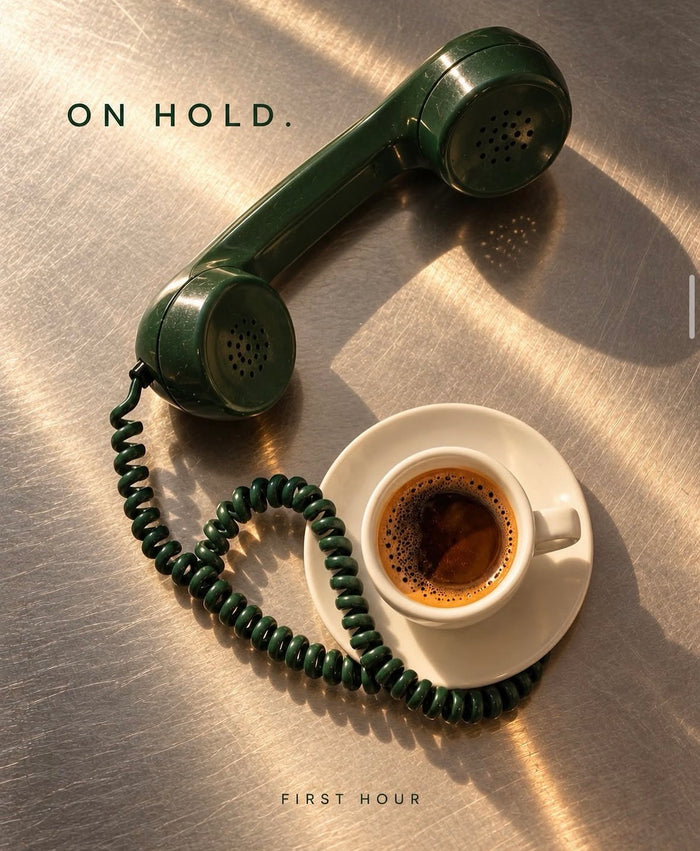 A green telephone handset resting beside a cup of coffee.